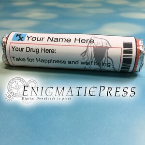 Op de afbeelding: Een grappige snoepreepverpakking die is ontworpen als een receptlabel. Het label bevat de tekst "Your Name Here", "Your Drug Here:" en "Take for Happiness and well being". De verpakking heeft zilverfolie uiteinden en een zwarte barcode.