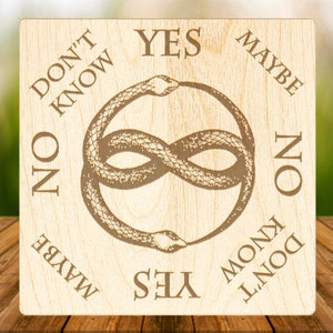 Op de afbeelding: Houten Ouija-bord met een slangontwerp in het midden. Het bord heeft de woorden "YES", "NO", "MAYBE", "DON'T KNOW" rond de rand geschreven.