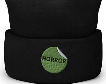 Peut inclure: Un bonnet noir avec un cercle vert brodé avec le mot "HORROR" en texte blanc.