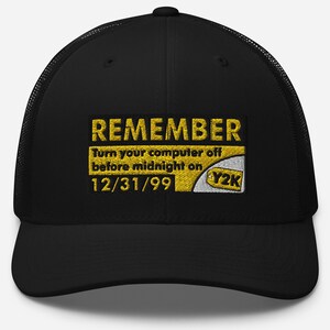 Puede incluir: Gorra de camionero negra con parte trasera de malla y visera curva. La parte delantera presenta un parche bordado amarillo con la palabra "REMEMBER" sobre el texto "Turn your computer off before midnight on 12/31/99" y un gráfico Y2K.