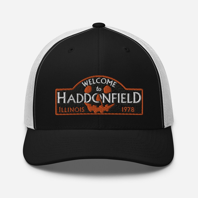 May include: Black and white trucker hat with a black and orange embroidered patch that says "Welcome to Haddonfield, Illinois 1978". The patch features a jack-o-lantern face.