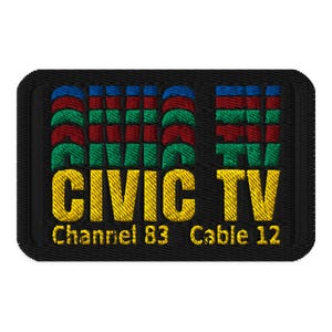 Puede incluir: Parche bordado con el texto "CIVIC TV" en amarillo, con las palabras "Channel 83 Cable 12" debajo. Las letras "CIVIC" están en un diseño apilado con colores rojo, verde y azul. El parche tiene un borde negro.