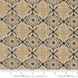 May include: Tan fabric with a repeating pattern of stylized floral and geometric shapes in shades of beige, gray, black, and gold. The design features a grid-like arrangement of circles and quatrefoils, creating a symmetrical and ornate look. The fabric has a ruler along the bottom.