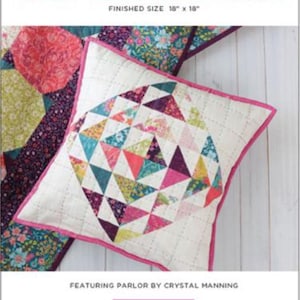 May include: A Boho Gem pillow cover with a geometric design. The pillow cover is white with a pink border and features a colorful patchwork of triangles in various floral patterns. Finished size is 18" x 18".
