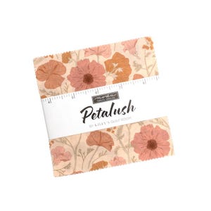 May include: A stack of square fabric pieces featuring a floral pattern in shades of peach, rust, and cream. A white paper band wraps around the center, printed with the text "moda FABRICS + SUPPLIES Petalush BY KILEY'S QUILT ROOM" and a ruler.