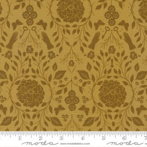 May include: A gold fabric with a repeating pattern of brown floral designs, leaves, and keys. The fabric has a subtle linen texture.