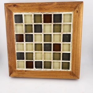 May include: A wooden framed square tile mosaic with a checkerboard pattern of brown, green, and white tiles.