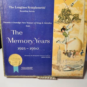 May include: Vintage record album titled "The Memory Years" from The Longines Symphonette Recording Society. The album cover features a blue background with gold accents and illustrations of the era, including an American flag and a rocket.