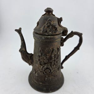 May include: A set of three ceramic mugs with a speckled, matte finish. The mugs are in shades of cream, gray, and black. Each mug has a simple, minimalist design, perfect for coffee or tea. The mugs are likely handmade.