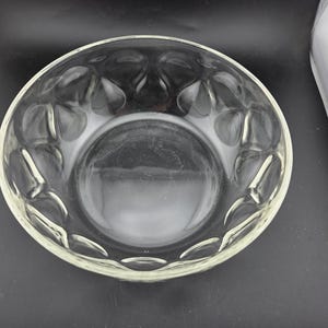 May include: Clear glass bowl with a decorative pattern around the rim. The bowl is round and has a wide opening, suitable for serving salads or displaying fruit. The glass is transparent, allowing the contents to be visible.
