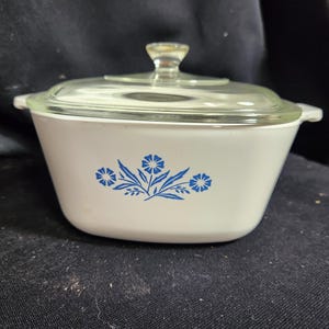 May include: White casserole dish with a blue floral design and a clear glass lid.