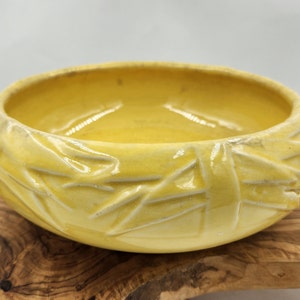 May include: A yellow ceramic bowl with a textured, woven design. The bowl is glazed and has a glossy finish.