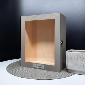 May include: A gray wooden shadow box with a glass front and a silver metal latch. The box has a label on the bottom that reads "The Moorman Family".