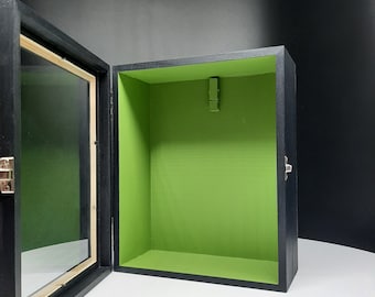 May include: A black wooden shadow box with a glass front and a green felt interior. The box has a hinged lid and a metal latch.