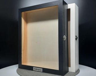 May include: A black wooden shadow box with a glass front and a white wooden back. The box has a silver latch and a silver nameplate that reads "The Memory Family".