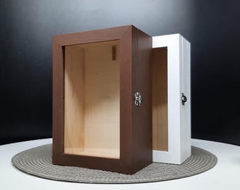 Peut inclure: Deux boîtes à ombre en bois avec des faces en verre. Une boîte est brune et l'autre est blanche. Les deux boîtes ont un petit loquet en métal.