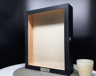 May include: Black wooden shadow box with a glass front and a silver plaque that reads "The Manning Family".
