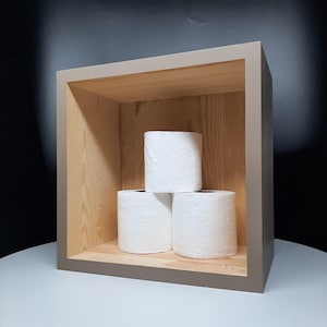 May include: Three rolls of white toilet paper with a floral pattern are stacked inside a wooden, open-faced box. The box has a light brown frame and a natural wood interior, set against a dark background.