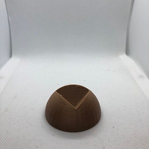 May include: A brown 3D printed object shaped like a half sphere with a triangular opening in the center.