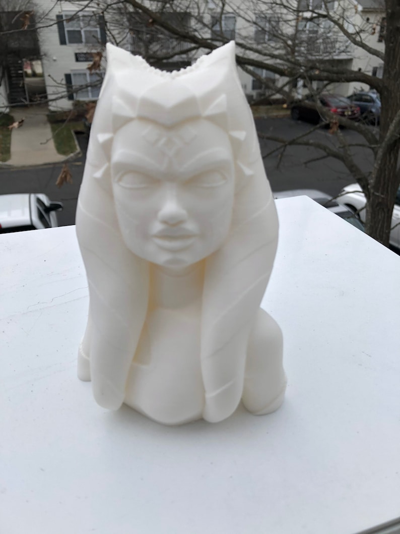 May include: White 3D printed bust of a woman with a detailed face and hair. The bust is on a white surface.
