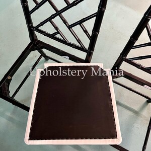 May include: Two black bamboo chairs with white cushions. The chairs have a diamond pattern and are in need of reupholstery.