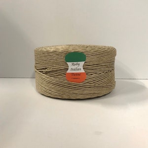 May include: A roll of natural brown Italian twine with a label that reads "Ruby Italian Twine".