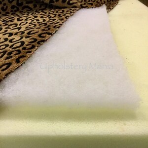 May include: Close-up of upholstery materials, including a white batting, a beige foam cushion, and a brown and tan leopard print fabric.
