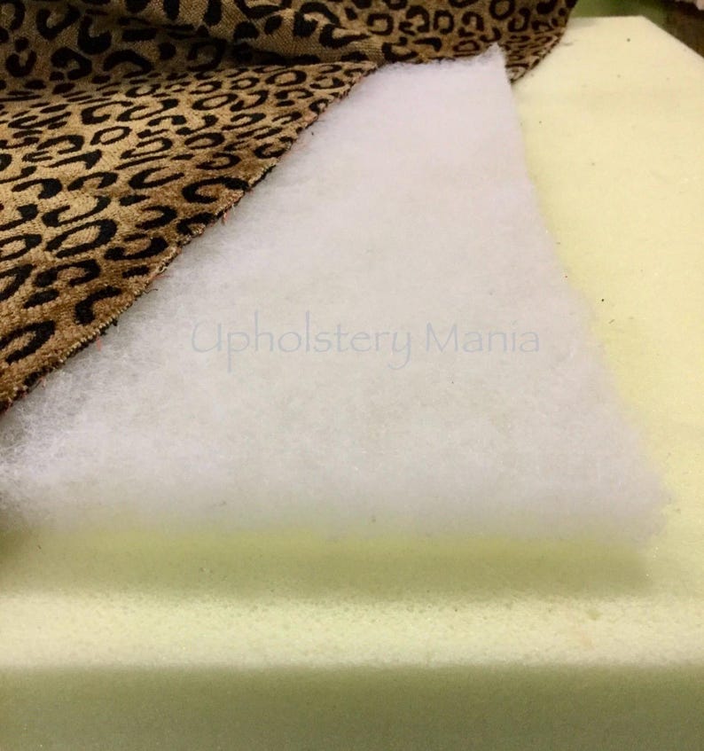 May include: Close-up of upholstery materials, including a white batting, a beige foam cushion, and a brown and tan leopard print fabric.