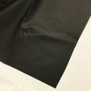 May include: Close-up of a black fabric with a textured weave. The fabric is folded and the corner is visible. The text "Upholstery Mania" is visible in the image.