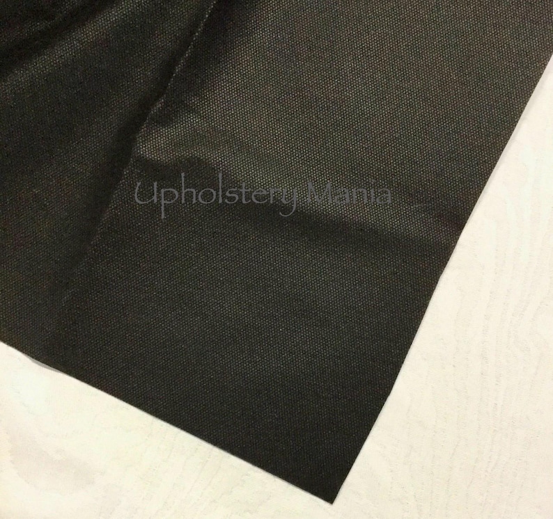 May include: Close-up of a black fabric with a textured weave. The fabric is folded and the corner is visible. The text "Upholstery Mania" is visible in the image.