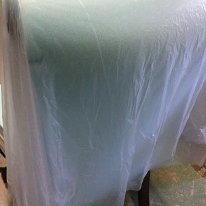May include: A teal upholstered chair with a plastic cover. The chair has a high back and a dark wood frame.