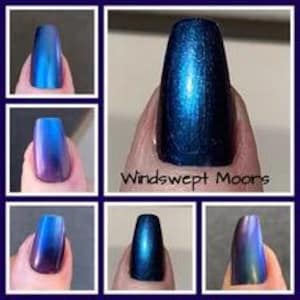 May include: A collection of nail polish swatches showing a deep blue and purple multichrome finish. The polish displays a metallic, colour-shifting effect with a smooth, glossy texture. The text "Windswept Moors" is printed below the central image.