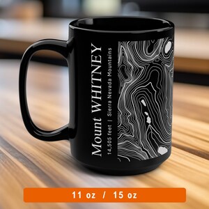 May include: Black ceramic mug with a white topographic map design of Mount Whitney, Sierra Nevada Mountains, 14,505 feet. The mug is 11 oz or 15 oz.