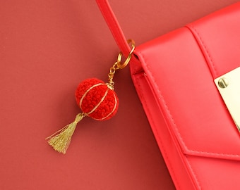 May include: A red leather handbag with a gold chain and a red tassel charm shaped like a Chinese lantern.