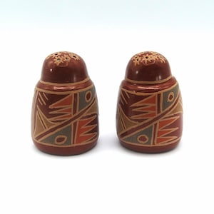 May include: A set of two brown ceramic salt shakers with geometric patterns in shades of orange, tan, and gray.