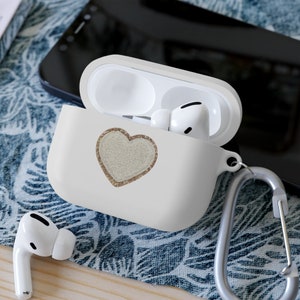 Peut inclure: Étui blanc pour Airpods avec un motif cœur en paillettes dorées et un mousqueton argenté.
