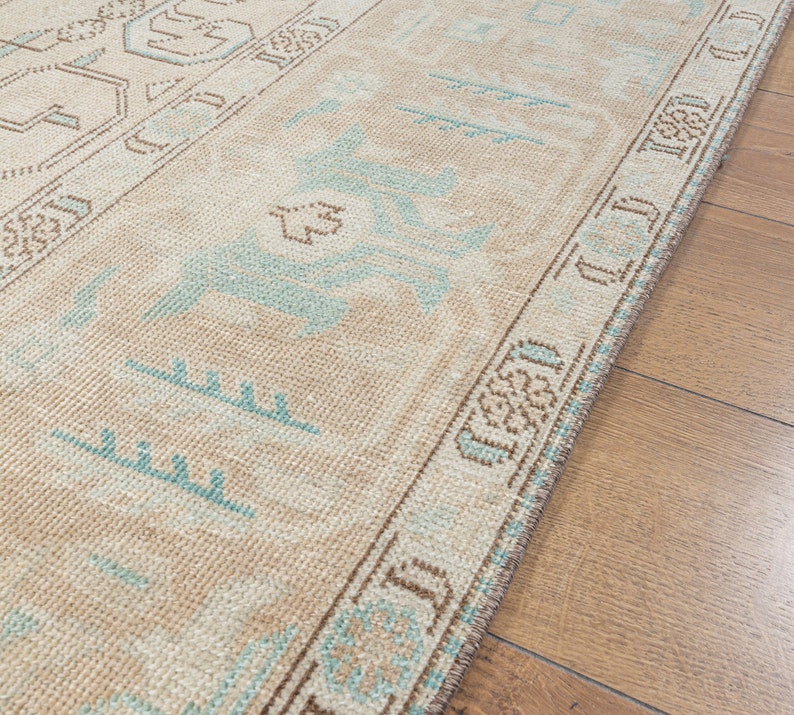 May include: A beige runner rug with a blue and brown geometric pattern. The rug has a fringe border.