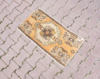 Puede incluir: Una alfombra rectangular tejida a mano con un fondo naranja cálido y intrincados patrones geométricos en marrón, beige y gris. El diseño de la alfombra presenta medallones centrales y motivos repetidos, ideal para añadir un toque bohemio a cualquier espacio.