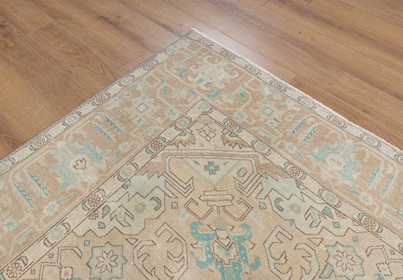 May include: A vintage rug with a beige background and a light blue geometric pattern. The rug has a fringe border.