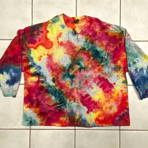 May include: A long-sleeved tie-dye shirt in a vibrant array of colors. The shirt features a crew neck and long sleeves, with a swirling pattern of red, yellow, blue, and green hues. The sleeves have a blue and red pattern.