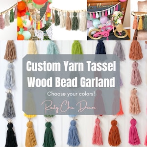 May include: A custom yarn tassel garland with wooden beads. The garland is made with a variety of colors, including green, blue, pink, yellow, and orange. The text "Custom Yarn Tassel Wood Bead Garland" and "Choose your colors!" is displayed on a gray background. The text "Rusty Chic Decor" is displayed on a white background.