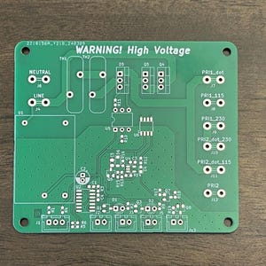 以下が含まれることがあります： 「WARNING! High Voltage」と印刷された緑色の回路基板。基板には、抵抗器、コンデンサ、集積回路など、いくつかの部品が搭載されています。また、基板にはいくつかのコネクタとテストポイントもあります。