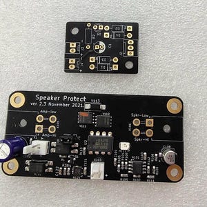 May include: A black circuit board with the text "Speaker Protect V113 ver 2.3 November 2021." The board has several components, including resistors, capacitors, and integrated circuits.