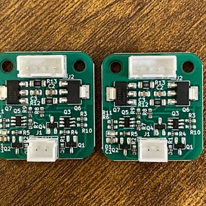 May include: Two green circuit boards with white connectors and black components. The boards have text on them, including "R11", "Q7", "Q5", "R9", "R12", "Q6", "Q3", "R3", "R10", "R1", "Q1", "R13", "C2", "C3", "J2", "J1", "R5", "R4", "R2", "D1", "C1", "C2", "R6", "R8", "R7", "D2", "Q2", "R1", "Q1", "R13", "C2", "C3", "J2", "J1", "R5", "R4", "R2", "D1", "C1", "C2", "R6", "R8", "R7", "D2", "Q2".
