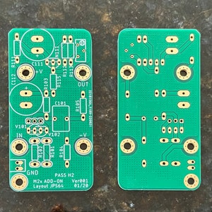 Puede incluir: Una placa de circuito impreso verde con componentes electrónicos, etiquetada como "PASS H2 M2x ADD-ON Ver001 Layout JPS64 01/20".