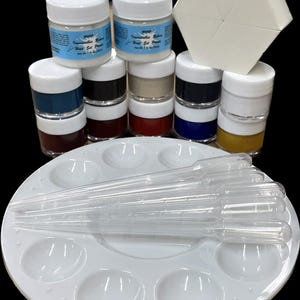 May include: A set of 10 small jars of acrylic paint, a white hexagonal sponge, a white plastic paint palette with 8 wells, and 6 clear plastic droppers. The paint jars are labeled "Irresistable Colors Heat-Set Paints".