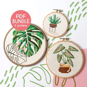 Pode incluir: Três padrões de bordado em aro que representam uma folha de monstera, uma planta em vaso com um gato e uma planta em vaso com um fundo geométrico. Os padrões estão sobre tecido branco e estão prontos para serem bordados.