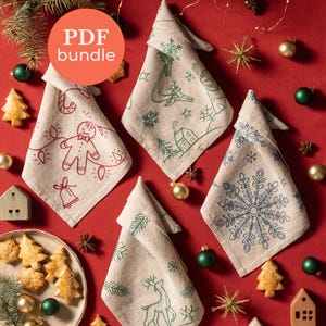 Puede incluir: Cuatro servilletas de lino plegadas con bordados navideños. Los diseños incluyen un hombre de jengibre, un reno, un copo de nieve y una escena invernal. Las servilletas son beige con bordados rojos y verdes, sobre fondo rojo.