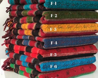 Peut inclure: Une pile de sept couvertures tissées colorées avec des franges. Les couvertures sont superposées dans une variété de couleurs, notamment le rouge, le vert, le bleu, le jaune et le noir. Chaque couverture a un motif différent et est étiquetée avec une lettre et un numéro, de F-1 à F-7.