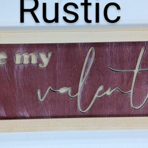 Handmade cypress frame with Baltic birch. The background is burgandy with white brush strokes. The natural Baltic birch letters read ...be my Valentine. Be my is in printed letters and the valentine in script. The words are recessed into the wood.